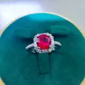 Macro shot of 2ct oval red ruby ring with halo diamonds on green velvet box - A5 Open Type / Red