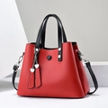 Red faux leather tote bag with black handles, a shoulder strap, and heart charms - Red