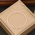 Pink natural stone beaded bracelet with rose quartz and gold spacers on a beige box - Pink