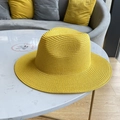 Detail of bright yellow straw sun hat with fine weave texture on marble surface - Yellow