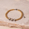 Detailopname van kralenarmband met sterhangers op steen met verfijnde metalen afwerking - Gouden Kralen Ster Stijl