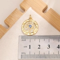 Macro view of gold Evil Eye pendant with white crystals and ruler for size scale - E007G