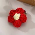 Handmade red knitted flower hair clip with yellow center on a soft grey background - Red