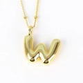 Macro view of gold balloon letter W pendant with shiny metallic texture and bead chain - Letter W