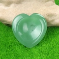 Polished heart-shaped green quartz worry stone placed on a natural rock in nature - Green Aventurine