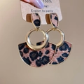 Detailopname van vintage luipaard oorbellen met gouden ringen en een waaiervormige textuur - Luipaard Waaier Stijl