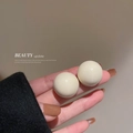 Close-up of elegant beige pearl stud earrings with smooth glossy finish and vintage style - Beige Spherical Pendant
