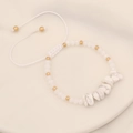 Detail of handmade beaded bracelet with white matte stones and gold accents on woven cord - White