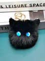 Detail of black faux fur pompom keychain with blue eyes and gold metal lobster clasp - Sapphire Blue