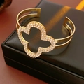 Detailed close-up of a gold clover bracelet with sparkling diamonds on a black leather gift box - Clover Open Style / Gold