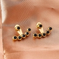 Dettaglio di orecchini ear jacket dorati con gemme nere disposte in modo curvo - N. 197 Nero / Nero
