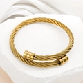 Elegante bracciale rigido a fune intrecciata dorata con estremità cilindriche su pietra - Oro