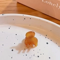 Mini pince à cheveux ambrée en résine sur une assiette en céramique blanche - Caramel