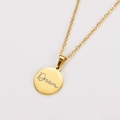 Detailed view of an 18k gold plated round pendant with Dream script engraving - Gold