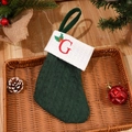 Dark green knitted Christmas stocking with red embroidered letter G and holly patterns - Letter G