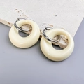 Dettaglio dei ciondoli ovali in resina crema con cerchi in argento su pietra di travertino - Acciaio-Beige