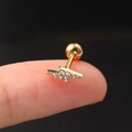 Macro shot of gold lightning bolt stud earring with white zircons on a fingertip - Flash / Gold (Lightning)