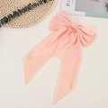 Close-up of pink silk bow hair clip with long ribbons on a decorative background - Pink