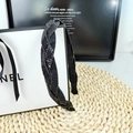 Detailed view of black braided headband with shimmering rhinestones on woven straw mat - Black