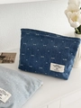 Dettaglio delle borse portaoggetti in denim con fiocchi ricamati su tavolo bianco - Blu scuro