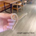 Gold-tone hair claw clip with faux pearls and rhinestones, length 7.0cm, handheld view - Cross Pearl & Rhinestone