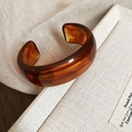 Macro shot of irregular geometric open bangle with polished amber tortoiseshell texture - Amber