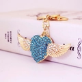 Exquisite gold winged heart keychain with blue crystals on a book background - Blue