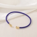 Close-up of a purple hand-woven cuff bracelet with polished gold metal end caps - Purple