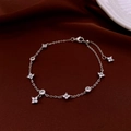 Detalle de pulsera de trébol plateada con circonitas sobre elegante seda burdeos - Plateado