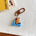 Close-up of cute Capybara riding a blue motorcycle keychain on a white canvas background - Electric Scooter Style