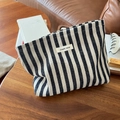 Detailed macro view of the vertical stripe canvas makeup bag with a zipper and fabric label - Striped