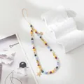 Detail of colorful beaded phone strap with gold stars on white minimalist background - Colorful