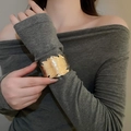 Dettaglio di un bracciale rigido aperto a forma di foglia dorata sul polso di una modella - Stile 43 - Oro