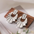 Dettaglio macro di orecchini d'argento a pieghe su supporto in legno con tulipani bianchi - Ventaglio Pieghettato / Argento