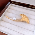 Dettaglio della spilla a foglia di ginkgo placcata oro 18K con perla lucida su velluto - Placcato Oro Vero Oro