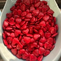Polished red heart-shaped stones with black vein patterns in a storage basket - Red Howlite with Black Veins