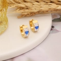 Golden hoop earrings with blue heart stones and diamonds on white ceramic tray - Sapphire Blue