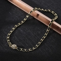 Close-up of a sparkling gold sphere pendant with inlaid zircons on a woven black cord chain - XL22 / Woven Ball / Gold Black