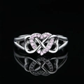 Macro detail of silver ring featuring interlocking hearts with pink pave-set zircons - US 7 / White Gold