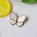 Detalle macro de broche de mariposa con alas de nácar e incrustaciones de cristales - Blanco