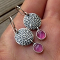 Vintage silver hammered earrings with pink oval jasper stones in a handheld macro shot - Rose Red