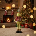 Close-up of a plush Grinch doll in a cozy Christmas living room near a holiday tree - Telescopic Green Monster ML-Q783