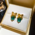 Macro shot of gold-plated crossover stud earrings with green square crystals in a jewelry box - Emerald Cube (WE5193) / Gold-Green