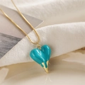 Detail of teal heart pendant with melting gold effect on a fine gold-colored chain - Teal