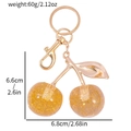 Dettaglio portachiavi ciliegia con dimensioni 6,6x6,8cm e sfere dorate glitterate - Stile Glitter Arancio-Giallo Brillante (KC2407)