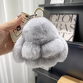 Close-up of a fluffy grey plush rabbit keychain with a gold ring held in hand - 10cm Bunny / Light Gray