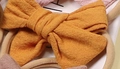 Soft nylon infant headband featuring a large ginger yellow cotton fabric bow detail - Orange