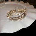 Macro detail of gold plated multi-layer spiral bracelet with sparkling crystal inlay on white tray - Style 29 / Gold