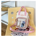 Detailansicht der rosa-weißen Ita-Tasche mit Klarsichtfenster auf einem gelben Stuhl - Weiß und Rosa