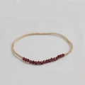 Close-up of minimalist beaded bracelet with faceted red stones and gold metal spacers - Garnet